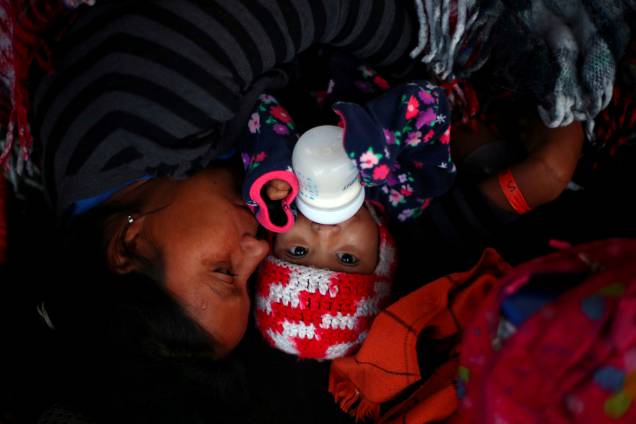 Mãe e bebê descansam enquanto aguardam para atravessar a fronteira entre o México e os Estados Unidos, na cidade de Tijuana - 23/11/2018