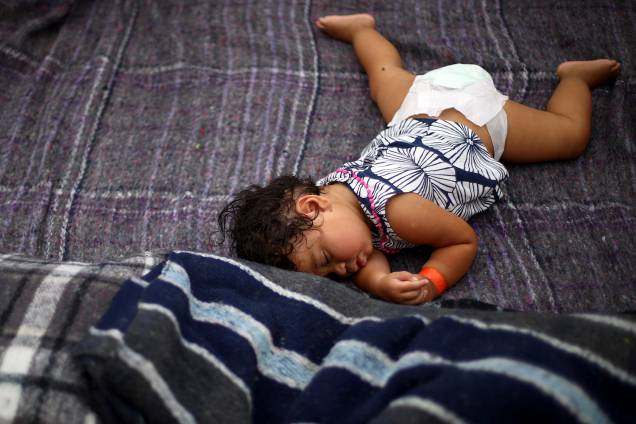 Garota descansa em acampamento improvisado montado por membros da caravana de imigrantes da América Central, nos arredores da fronteira entre o México e os Estados Unidos, na cidade de Tijuana - 24/11/2018
