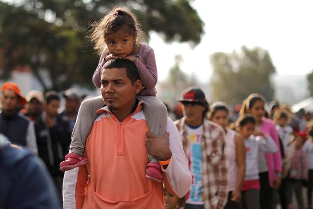 Membros da caravana de imigrantes da América Central fazem fila para receberem comida em acampamento improvisado, montado nos arredores da fronteira entre o México e os Estados Unidos, na cidade de Tijuana - 24/11/2018