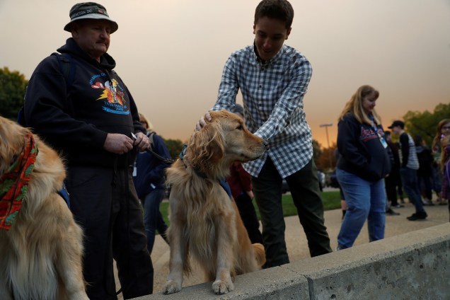 Reuben, um cão treinado para auxiliar pessoas em situações de trauma, é acariciado por um homem no estacionamento da igreja Luterana de Chico, usado como abrigo de emergência para os deslocados do Camp Fire, na Califórnia - 11-11/2018