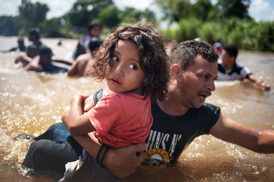 Pai carrega filho durante passagem pelo rio Suchiate, localizado na cidade mexicana de Ciudad Hidalgo, durante caravana de imigrantes da América Central, rumo aos Estados Unidos - 29/10/2018