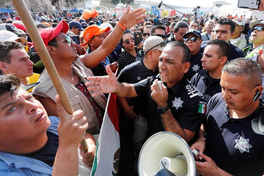 Migrantes negociam com policiais para atravessarem fronteira entre o México e os Estados Unidos, na cidade de Tijuana - 22/11/2018