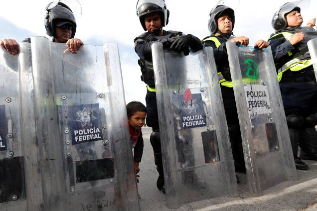 Criança é vista atrás de escudo de policial mexicano, próxima da fronteira entre o México e os Estados Unidos, na cidade de Tijuana - 22/11/2018