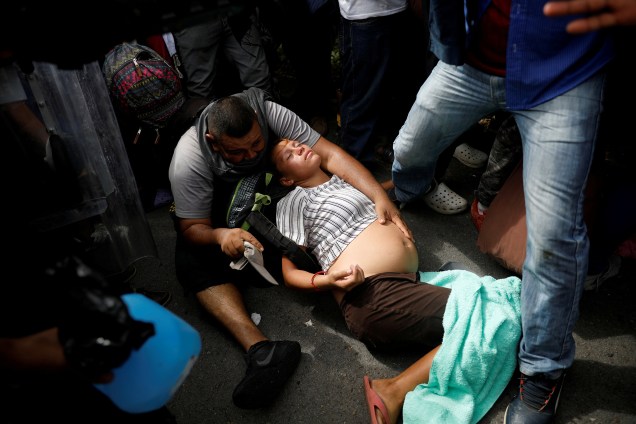 Imigrante grávida, parte da caravana de El Salvador que tenta entrar nos Estados Unidos desmaia durante uma operação da polícia mexicana para detê-los por entrar ilegalmente no país, em Metapa - 21/11/2018