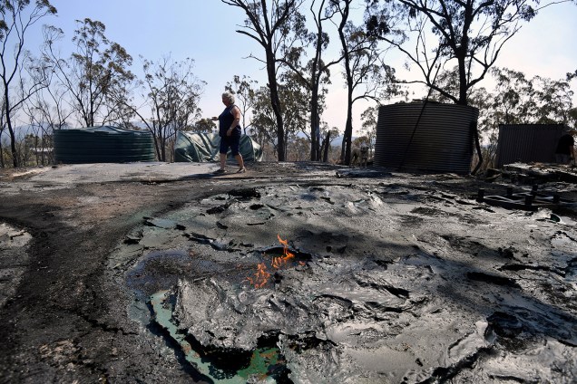 Jeanette Schwindt, residente local, inspeciona seu galpão e tanques de água destruídos depois que um incêndio florestal varreu a área no Monte Larcom em Queensland, Austrália - 29/11/2018