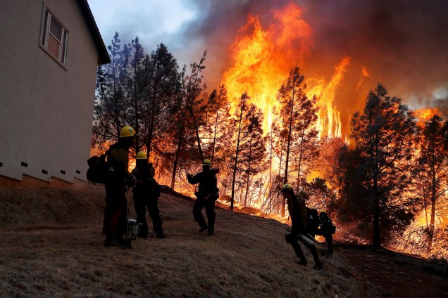 Membros do Serviço Florestal dos EUA trabalham para conter chamas que avançam para cima de uma casa durante o incêndio florestal que atingiu a cidade de Paradise, na Califórnia - 08/11/2018