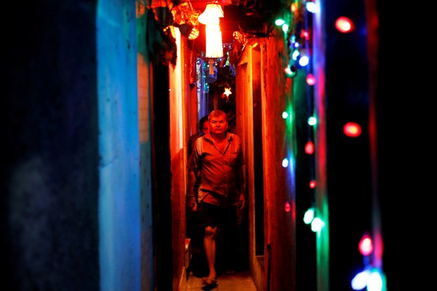 Moradores caminham em beco de uma favela iluminado por luzes coloridas às vésperas do festival hindu Diwali em Mumbai, na Índia - 06/11/2018