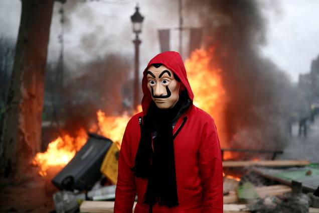 Manifestante caminha em frente a uma barricada durante protesto contra o aumento no preço dos combustíveis na Champs-Elysees, em Paris, França - 24/11/2018