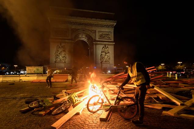 Manifestante coloca uma bicicleta em uma barricada em chamas durante protesto contra o aumento dos preços dos combustíveis e do custo de vida perto do Arco do Triunfo em Paris - 24/11/2018