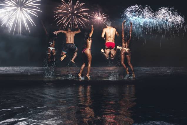 Grupo de amigos pulam ondas durante celebração de Ano Novo