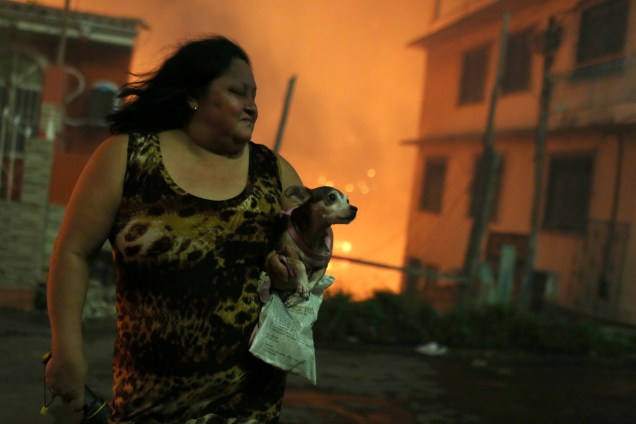 Mulher carrega seu cachorro após deixar sua casa durante incêndio de grandes proporções no bairro de Educandos, zona sul de Manaus - 17/12/2018