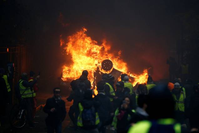 Manifestantes de colete amarelo são vistos próximos a um carro em chamas durante protesto na Place de l'Etoile em Paris, França - 01/12/2018