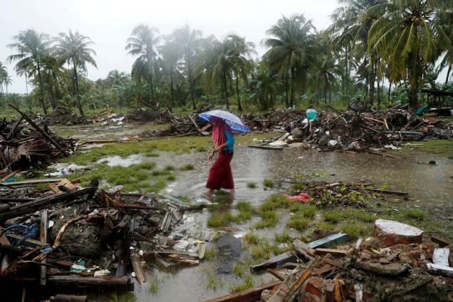 Mulher caminha pelos escombros causados pelo tsunami que atingiu a Indonésia, na cidade de Sumur - 26/12/2018