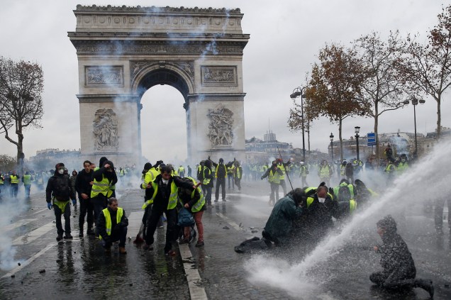 Manifestantes vestindo coletes amarelos, um símbolo de um protesto de motoristas franceses contra impostos mais altos no diesel, enfrentam a polícia de choque francesa durante os confrontos na Place de l'Etoile, perto do Arco do Triunfo, em Paris - 01/12/2018