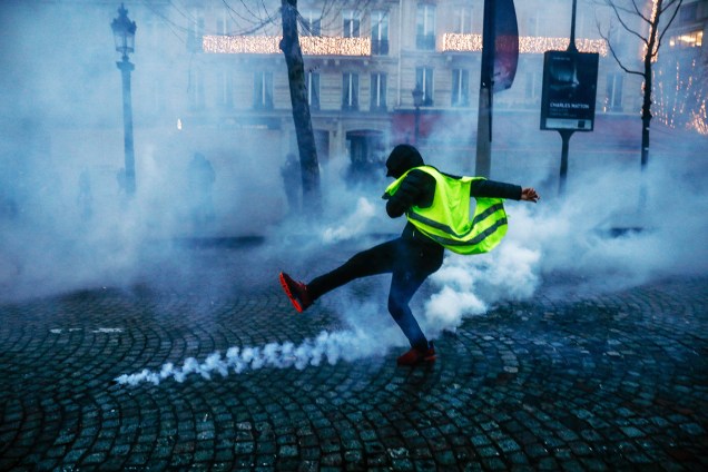 Manifestante com colete amarelo chuta artefato arremessado por policiais franceses durante protesto contra o governo em Paris  15/12/2018