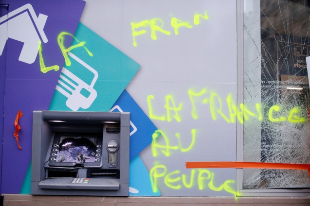 Uma pixação é vista ao lado de um caixa eletrônico depredado no dia seguinte das manifestações em Paris - 02/12/2017