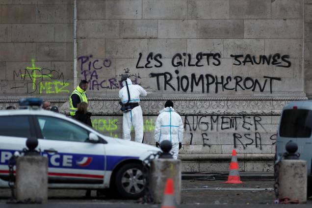 Policiais trabalham em torno da mensagem feita no Arco do Triunfo "Os coletes amarelos triunfarão", escrita durante as manifestações da última noite em Paris - 02/12/2018