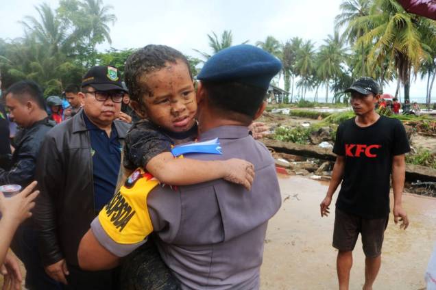 Garoto ferido é carregado por policial durante evacuação do hotel atingido por tsunami no distrito de Carita, localizado na província de Banten, na Indonésia - 23/12/2018
