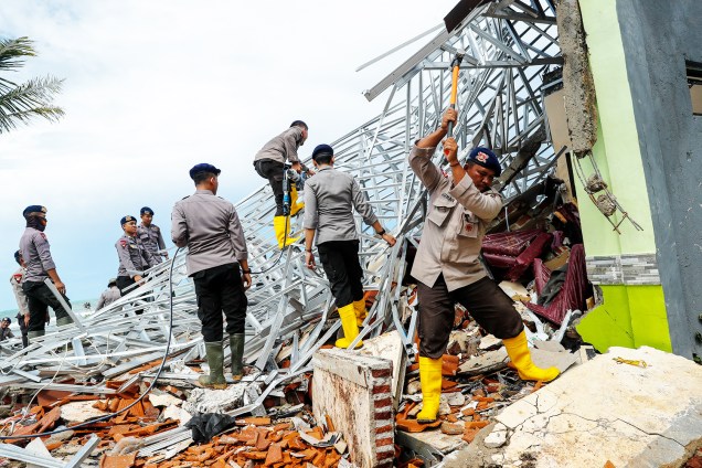Policiais procuram vítimas entre escombros após forte tsunami atingir a a regência de Pendeglang, na Indonésia - 24/12/2018