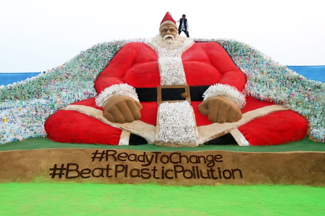 O artista indiano Sudarsan Patnaik finaliza escultura que representando o Papai Noel, feita com areia e garrafas plásticas, com a mensagem ´Beat Plastic Pollution' - tema do Dia Mundial do Meio Ambiante deste ano, na praia de Puri, localizada nos arredores da cidade indiana de Bhubaneswar - 24/12/2018