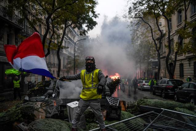 Manifestante usando um colete amarelo, símbolo dos protestos contra medidas econômicas do governo de Emmanuel Macron segura uma bandeira francesa durante ato em Paris - 01/12/2018