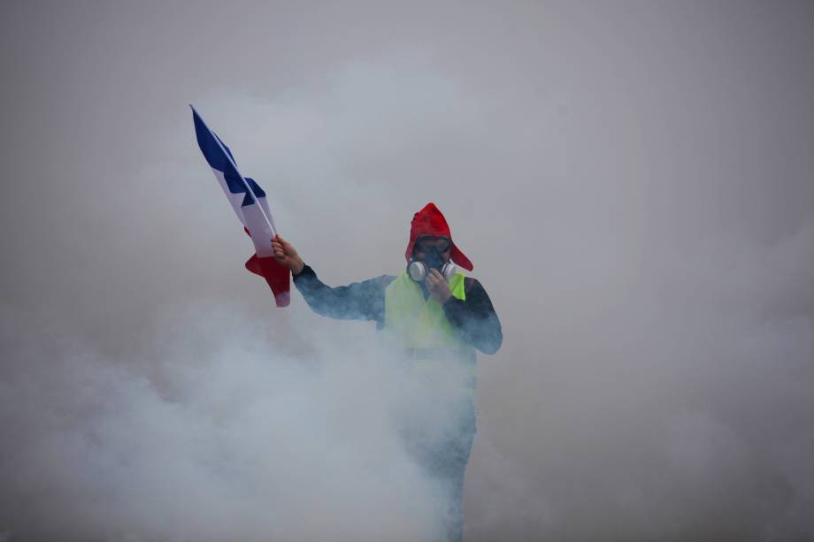 Manifestante segura uma bandeira francesa em meio à fumaça de gás lacrimogêneo durante protesto contra o aumento dos preços do diesel e do custo de vida em Paris - 01/12/2018