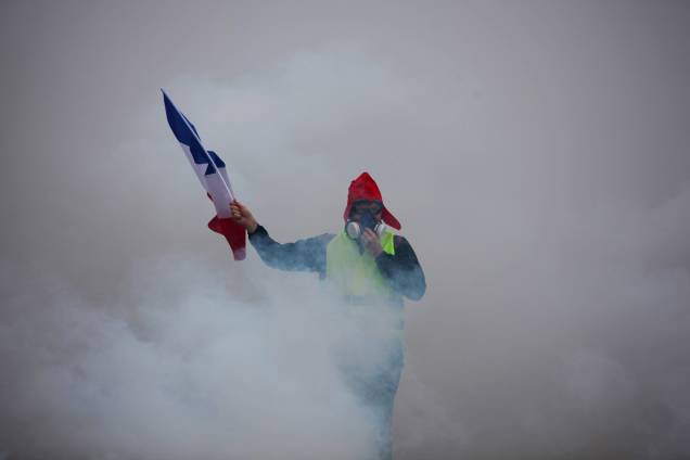 Manifestante segura uma bandeira francesa em meio à fumaça de gás lacrimogêneo durante protesto contra o aumento dos preços do diesel e do custo de vida em Paris - 01/12/2018