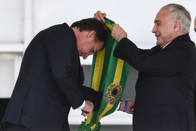 Presidente Jair Bolsonaro recebe a faixa presidencial do ex-presidente Michel Temer após subir a rampa do Palácio do Planalto, em Brasília - 01/01/2019