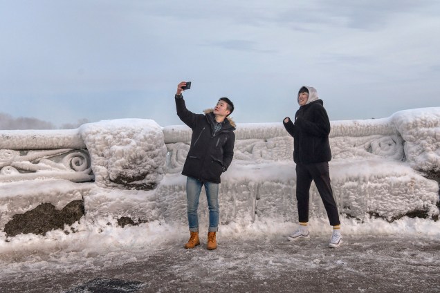 Visitantes tiram uma selfie nas Cataratas do Niágara, que teve boa parte das estruturas e quedas d'água congeladas devido às temperaturas abaixo de zero - 23/01/2019