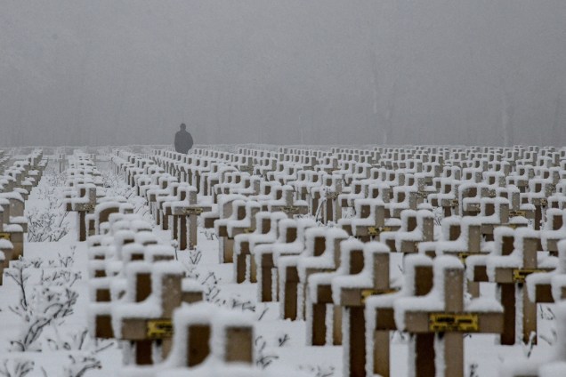 Homem caminha entre túmulos cobertos de neve no Cemitério Militar de Notre-dame de Lorette em Souchez, França - 23/01/2019