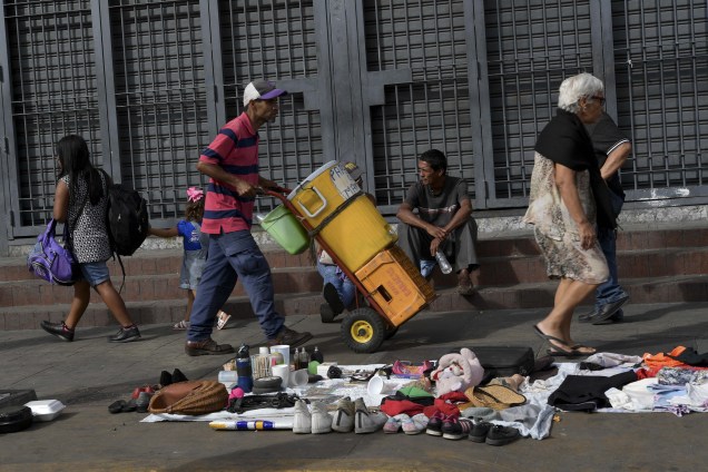 Pedestres caminham em frente a roupas, sapatos e outros artigos usados para venda ou troca em Caracas, Venezuela - 03/01/2019
