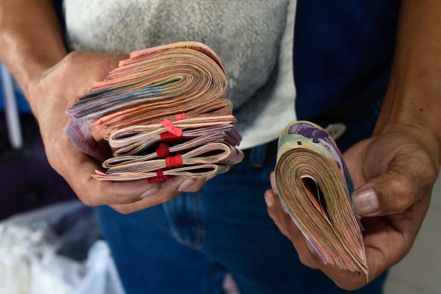 Homem segura cédulas de bolívar, a moeda oficial da Venezuela para pagar por uma passagem na rodoviária de Caracas - 03/01/2019