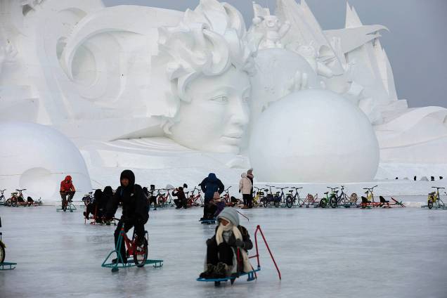 Pessoas brincam no gelo em frente a uma escultura de neve parte do Festival Internacional de Esculturas de Gelo e Neve de Harbin, província de Heilongjiang, China - 04/01/2019 Pessoas brincam no gelo em frente a uma escultura de neve parte do Festival Internacional de Esculturas de Gelo e Neve de Harbin, província de Heilongjiang, China - 04/01/2019