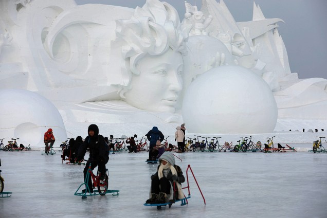 Pessoas brincam no gelo em frente a uma escultura de neve parte do Festival Internacional de Esculturas de Gelo e Neve de Harbin, província de Heilongjiang, China - 04/01/2019