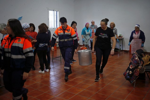 Membro da Proteção Civil e voluntário carregam comida para a equipe de resgate em Totalan, Espanha - 21/01/2019