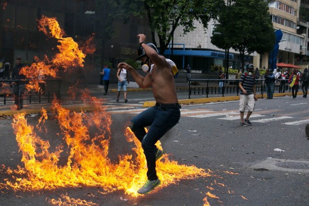 Manifestante salta sobre fogo durante protesto contra o governo do presidente venezuelano Nicolás Maduro, em Caracas - 23/01/2019