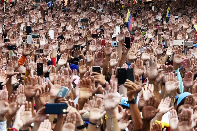 Manifestantes erguem as mãos durante juramento solene de Juan Guaidó, que se declarou presidente interino da Venezuela, durante marcha contra o governo de Nicolás Maduro, em Caracas - 23/01/2019