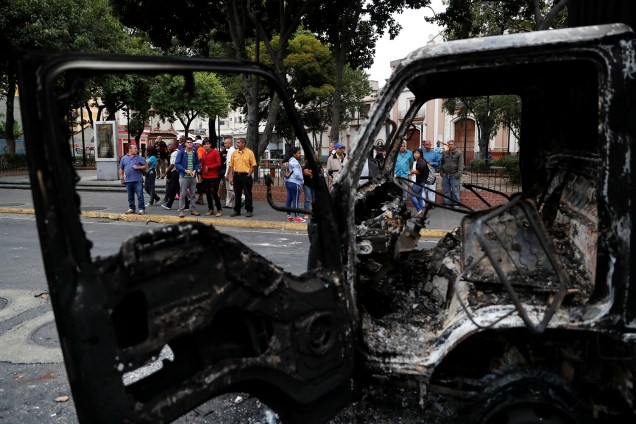 Pessoas observam um caminhão que foi queimado durante os protestos contra o governo de Nicolas Maduro em Caracas, Venezuela - 24/01/2019