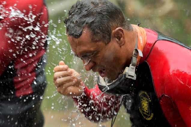 Membro da equipe de resgate recebe jatos de água para remoção de lama proveniente do rompimento de barragem em Brumadinho - 13/02/2019