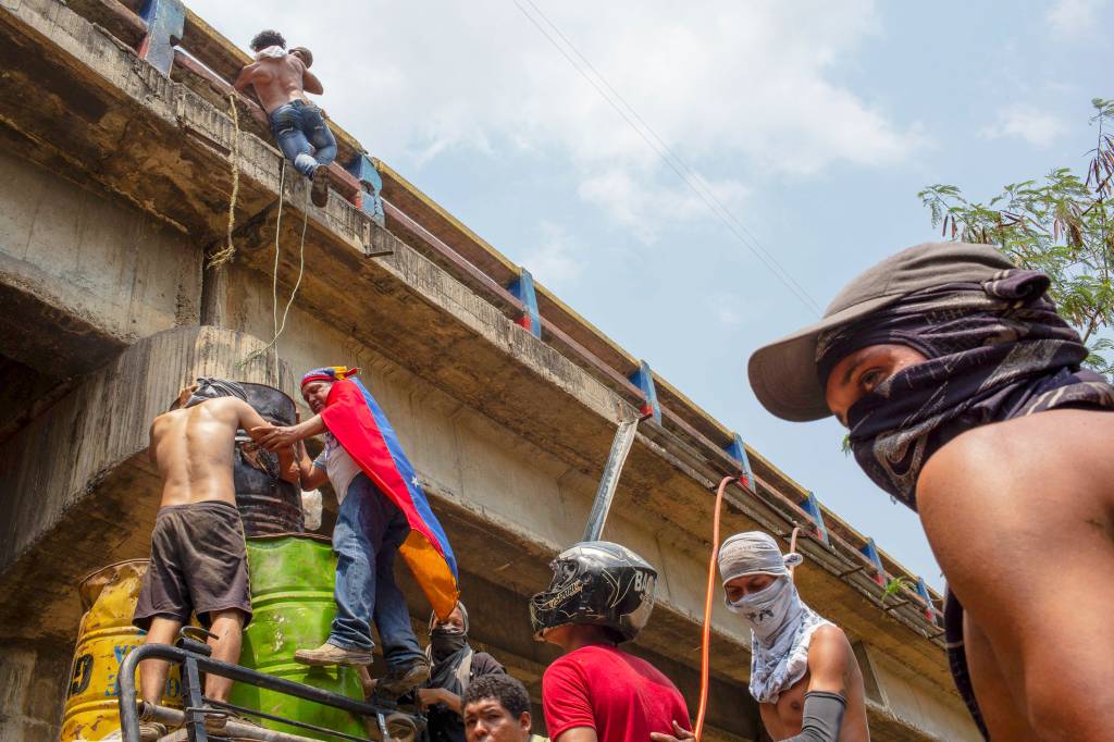 Jovens improvisam uma escada para subir na Ponte Francisco de Paula Santander, que liga as cidades de Cúcuta, na Colômbia, a Ureña, na Venezuela, para atacar soldados da Guarna Nacional Bolivariana