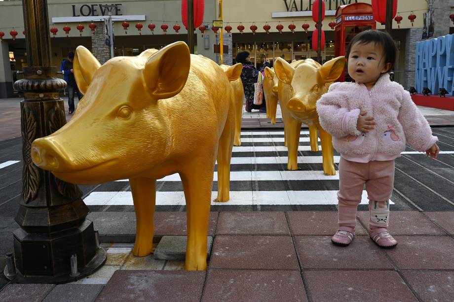 Menininha posa ao lado de escultura de porco em comemoração ao Ano Novo Lunar em Taoyuan, Taiwan - 25/01/2019