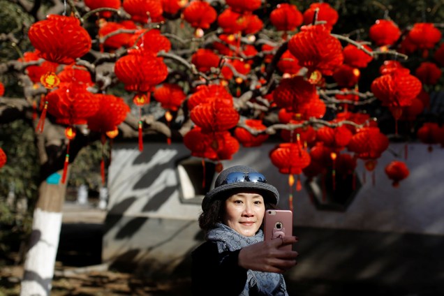 Mulher tira selfie em frente a árvore decorada com lanternas vermelhas para as celebrações de Ano Novo Lunar no Parque Ditan em Pequim, China - 01/02/2019