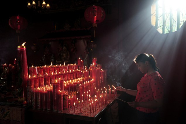 Mulher acende velas enquanto reza durante as celebrações do Ano Novo Lunar chinês em um templo em Jambi, na Indonésia - 05/02/2019