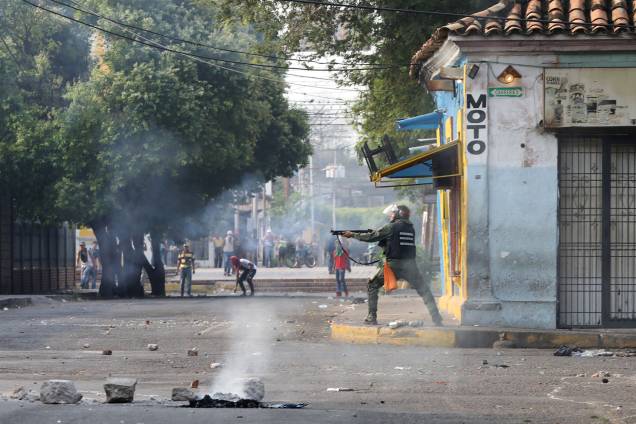 Membro da força de segurança da Venezuela aponta sua espingarda durante confronto com os manifestantes em Ureña, Venezuela - 23/02/2019