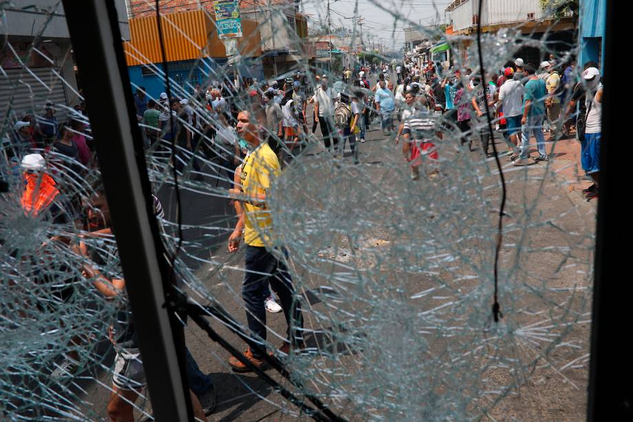 Manifestantes são vistos através de vidro quebrado de ônibus durante confronto com a guarda nacional em Ureña, Venezuela - 23/02/2019