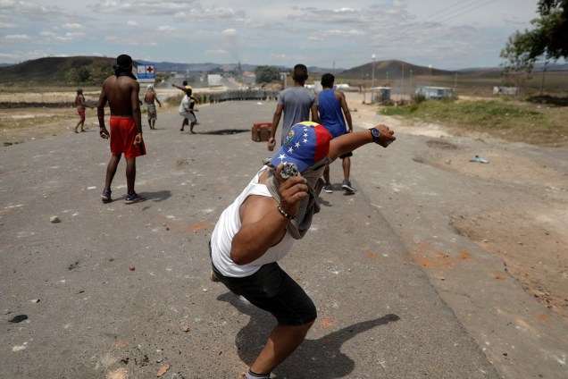 Homem atira pedra contra a guarda nacional venezuelana na fronteira da Venezuela com o Brasil em Pacaraima, Roraima - 24/02/2019