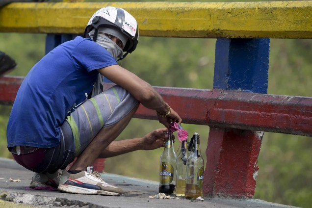 Manifestante prepara coquetéis molotov  durante confronto na fronteira da Venezuela com a Colômbia em Ureña, Venezuela - 24/02/2019
