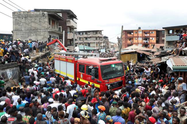 People gather as rescue workers search for survivors at the site of a collapsed building containing a school in Nigeria’s commercial capital of Lagos