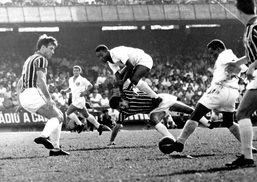 11 de outubro de 1964 - Em jogo contra o São Paulo, Pelé salta sobre o zagueiro Roberto Dias à espera do passe de Coutinho (com a bola), que é observado por Bellini, no Estádio do Morumbi, pelo Campeonato Paulista de Futebol