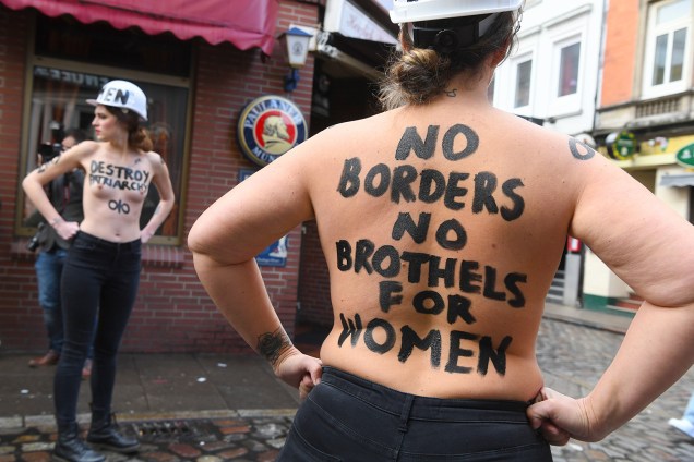 Membro do movimento feminista Femen com a frase: "Sem fronteiras, sem bórdeis para mulheres" escrita em seu corpo, posa para foto na Herbertstrasse, uma rua no distrito da luz vermelha pavimentada com bordéis e reservada apenas a homens, durante o Dia da Internacional Mulher, em Hamburgo, norte da Alemanha - 08/03/2019